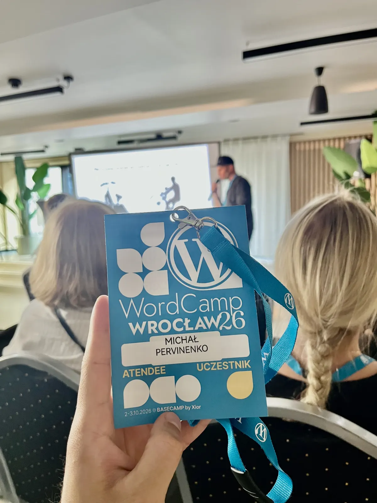 Identyfikator uczestnika WordCamp Wrocław 2026 – Michał Pervinenko z ITPER na sali prelekcyjnej